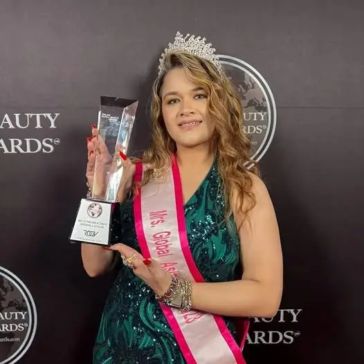 A crowned pageant honoree holding a beauty award